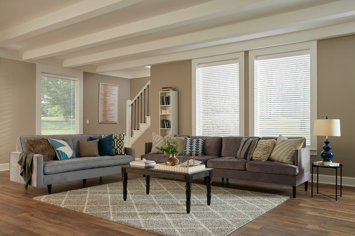 Large living room with blue accents and white light filtering wood blinds